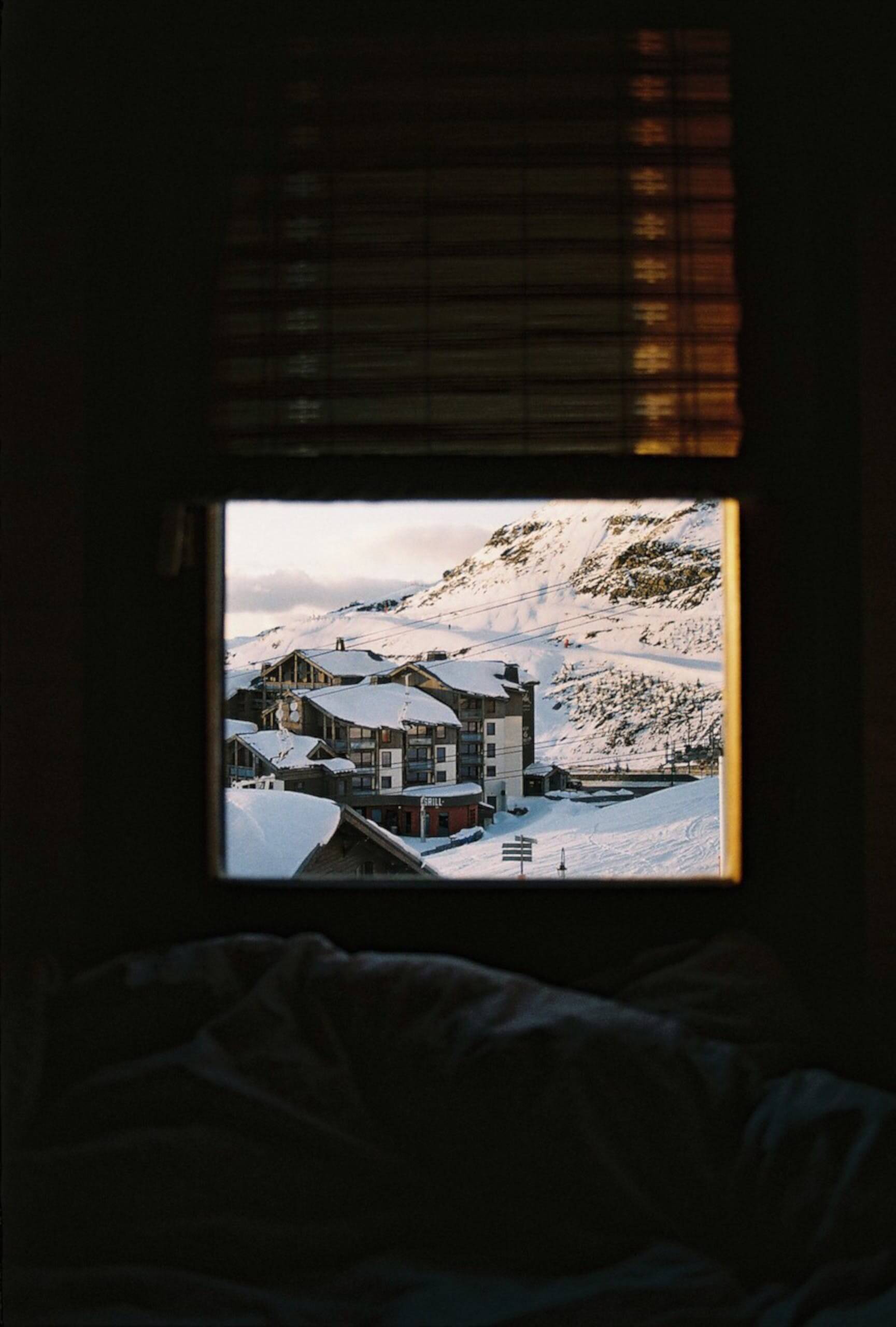 Photo of a mountainous, snow-capped villiage taken from within a building's window