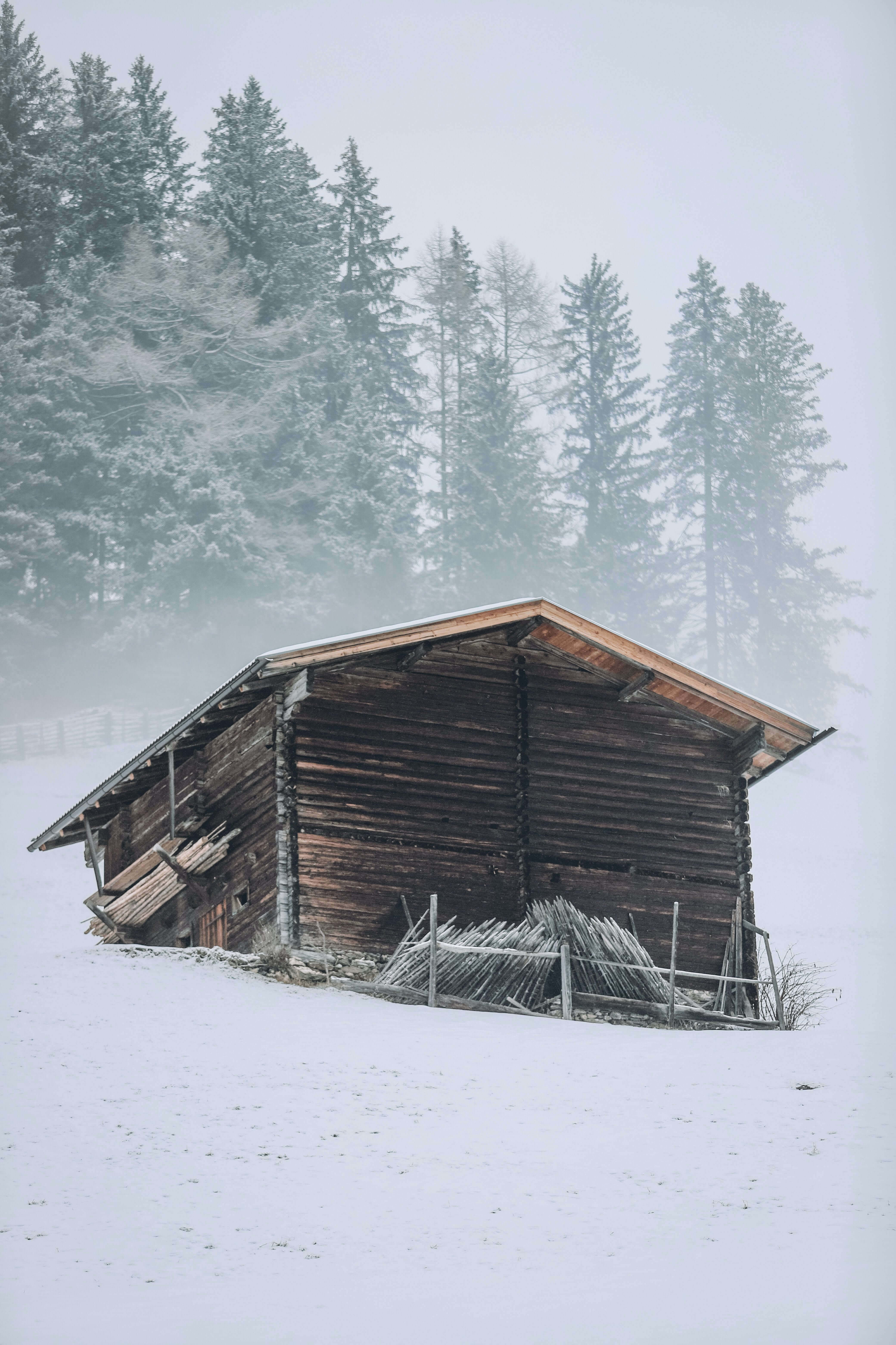 Photo of a small cabin home perched upon a snowy mountain